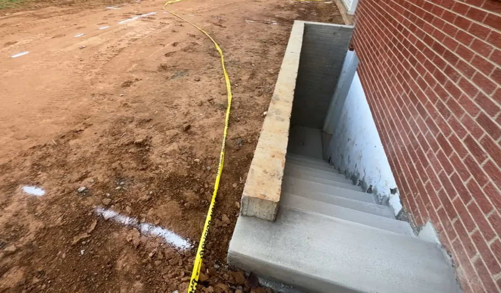 Finished concrete stairs for a basement egress entrance before final yard grading