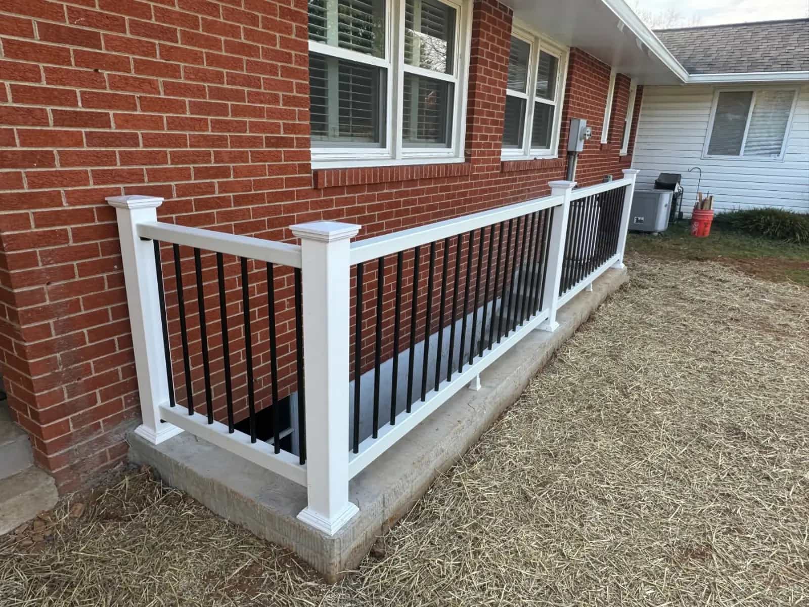 Finished basement egress entrance with white and black railing along the exterior wall