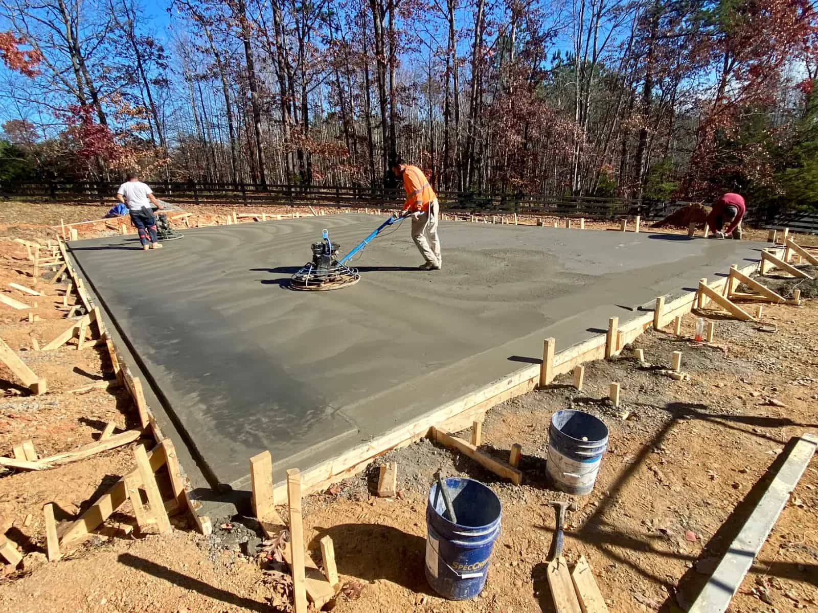 Crew finishing a large residential concrete foundation slab