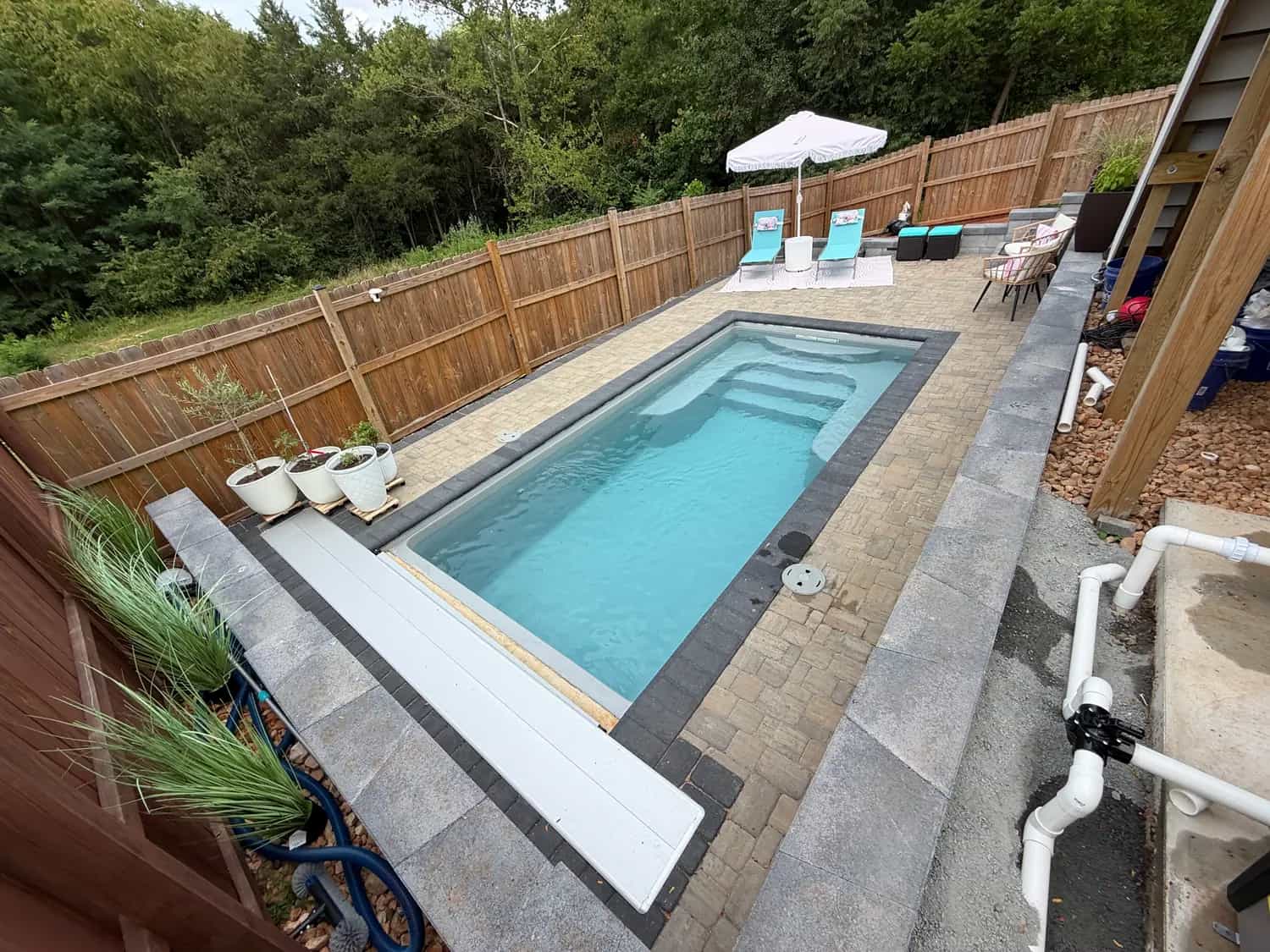 Finished fiberglass pool with paver patio, privacy fence, lounge chairs, and backyard outdoor living space in Culpeper VA