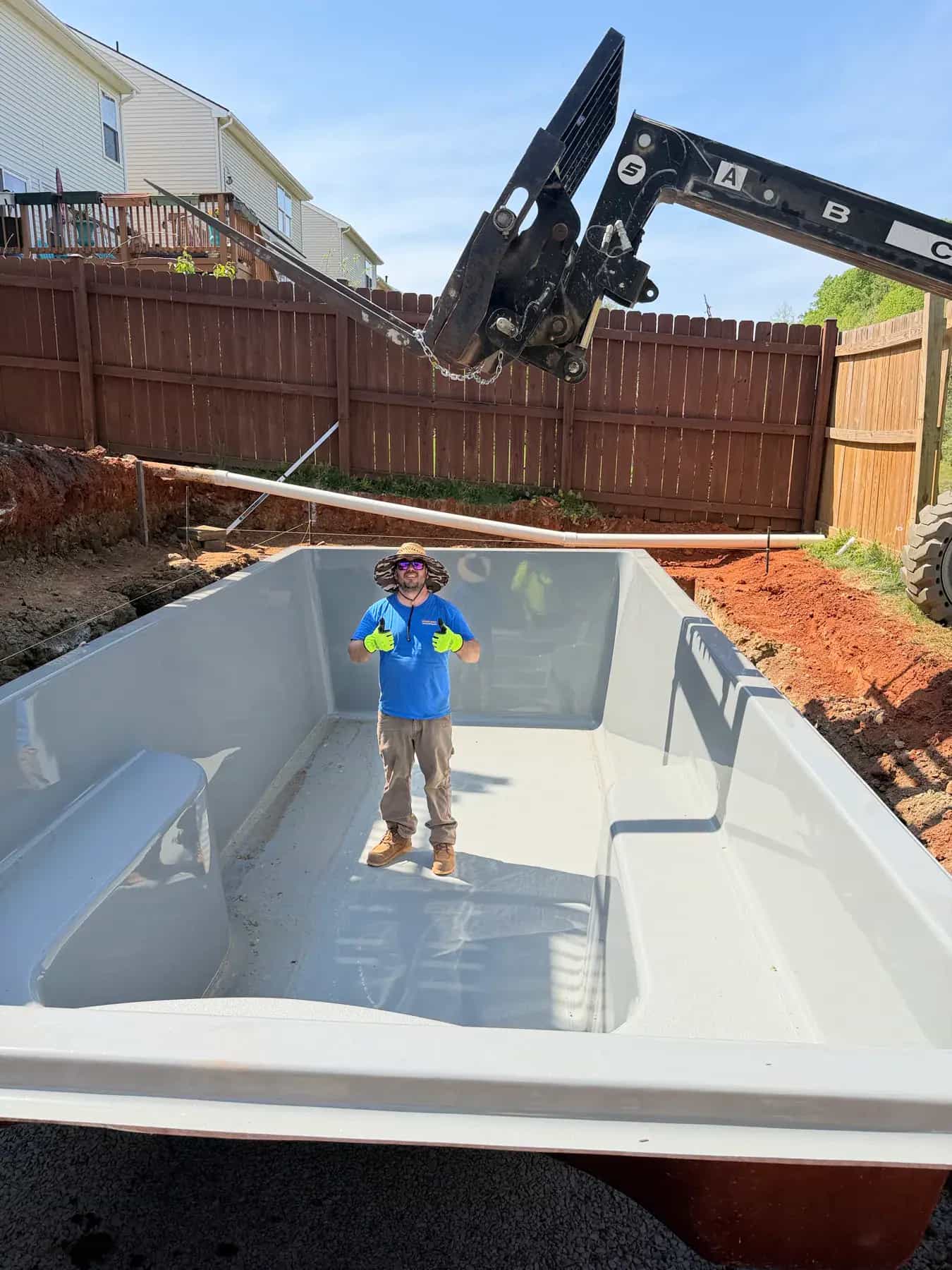 Fiberglass pool shell being placed during backyard pool installation