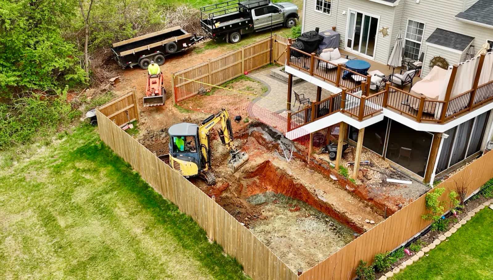 Aerial view of pool excavation and equipment access in a fenced backyard
