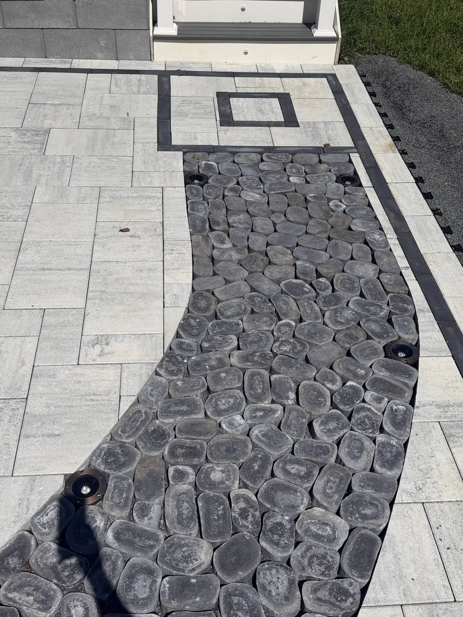 Close-up of the black cobblestone curve, fitted paver cuts and square accent near the stairs