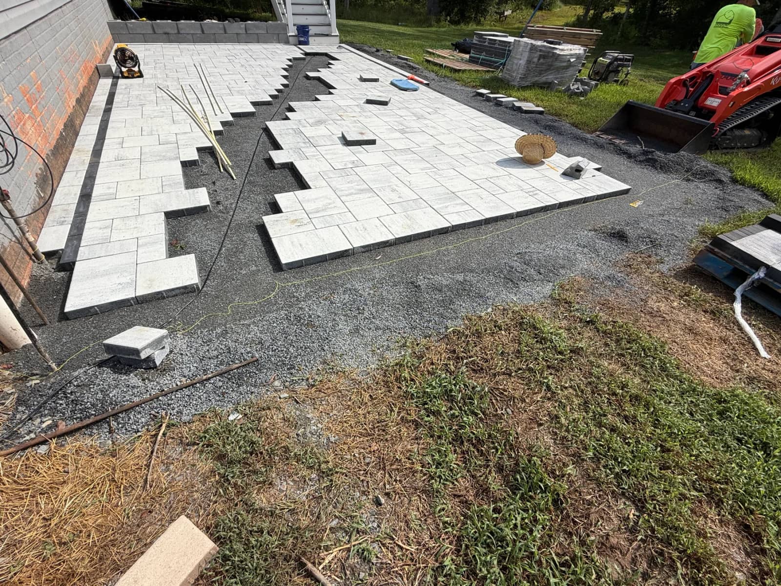 Paver installation in progress with the curved feature still open between the light-colored pavers