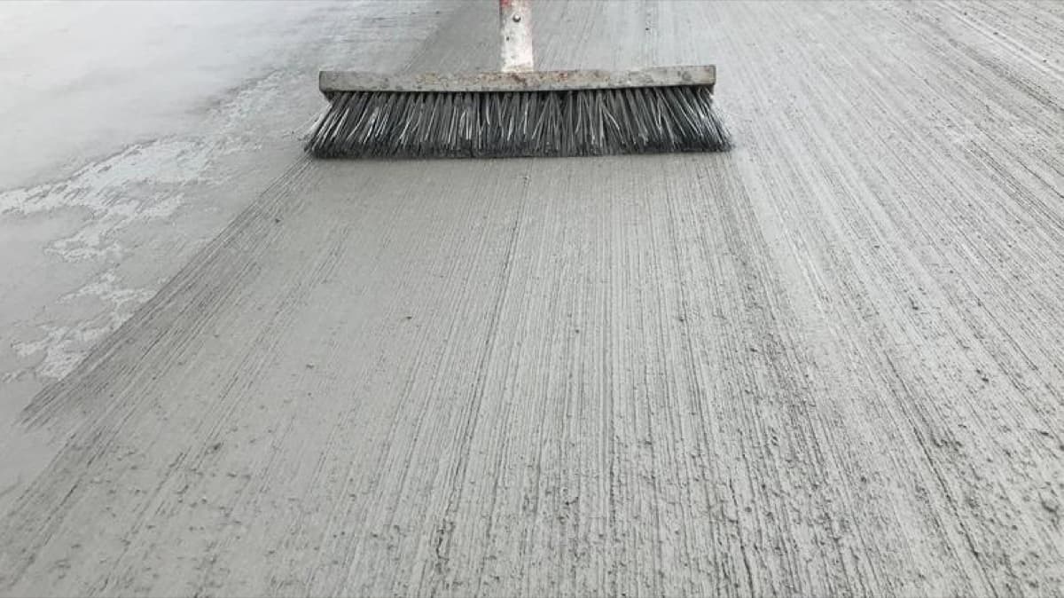 Broom being pulled across fresh concrete to create a practical slip-resistant finish