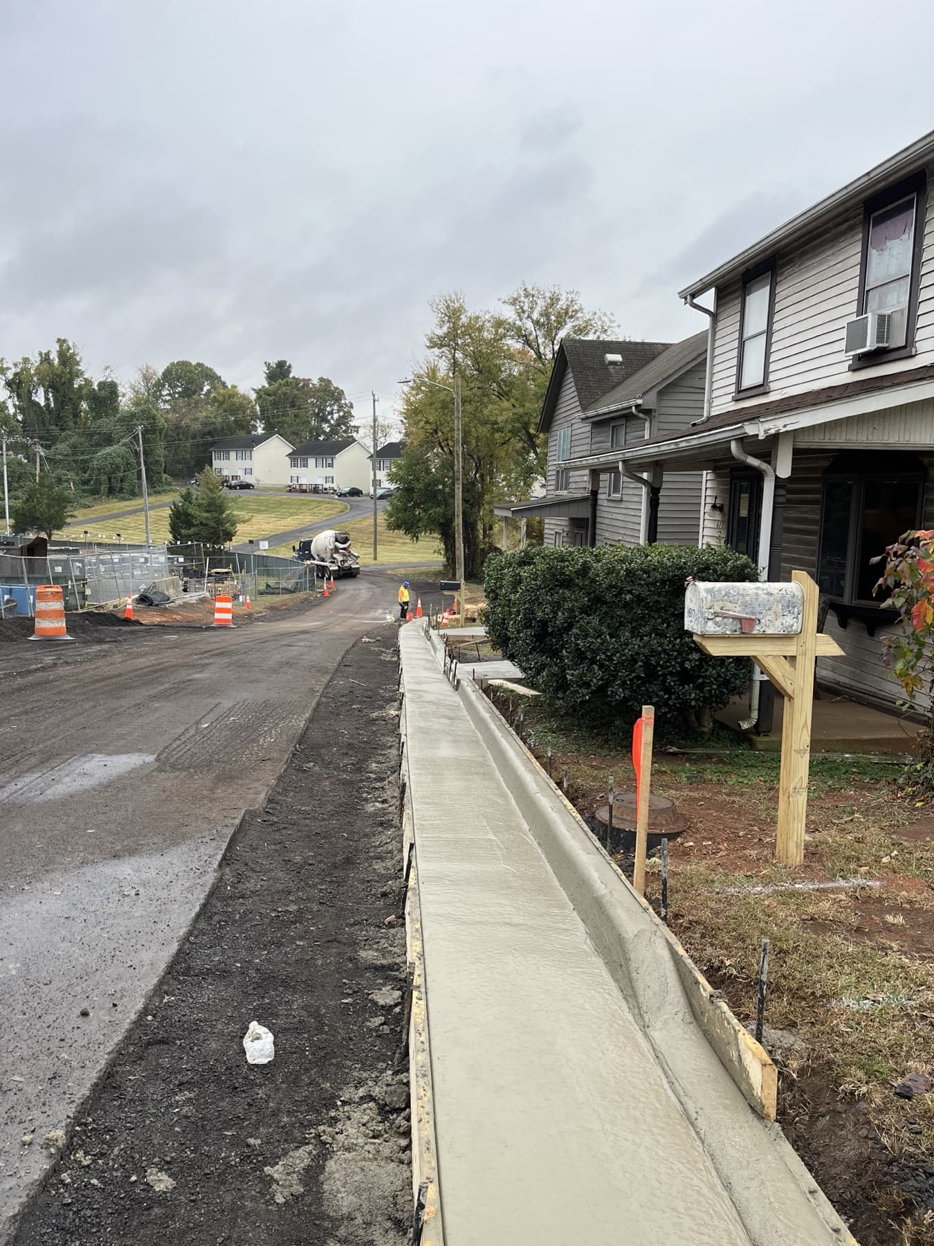Fresh commercial sidewalk concrete poured beside curb forms and site access