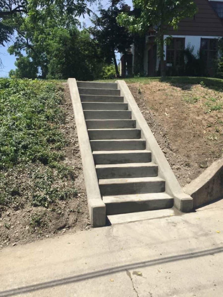 Finished concrete stairs with cheek walls on a sloped front entry