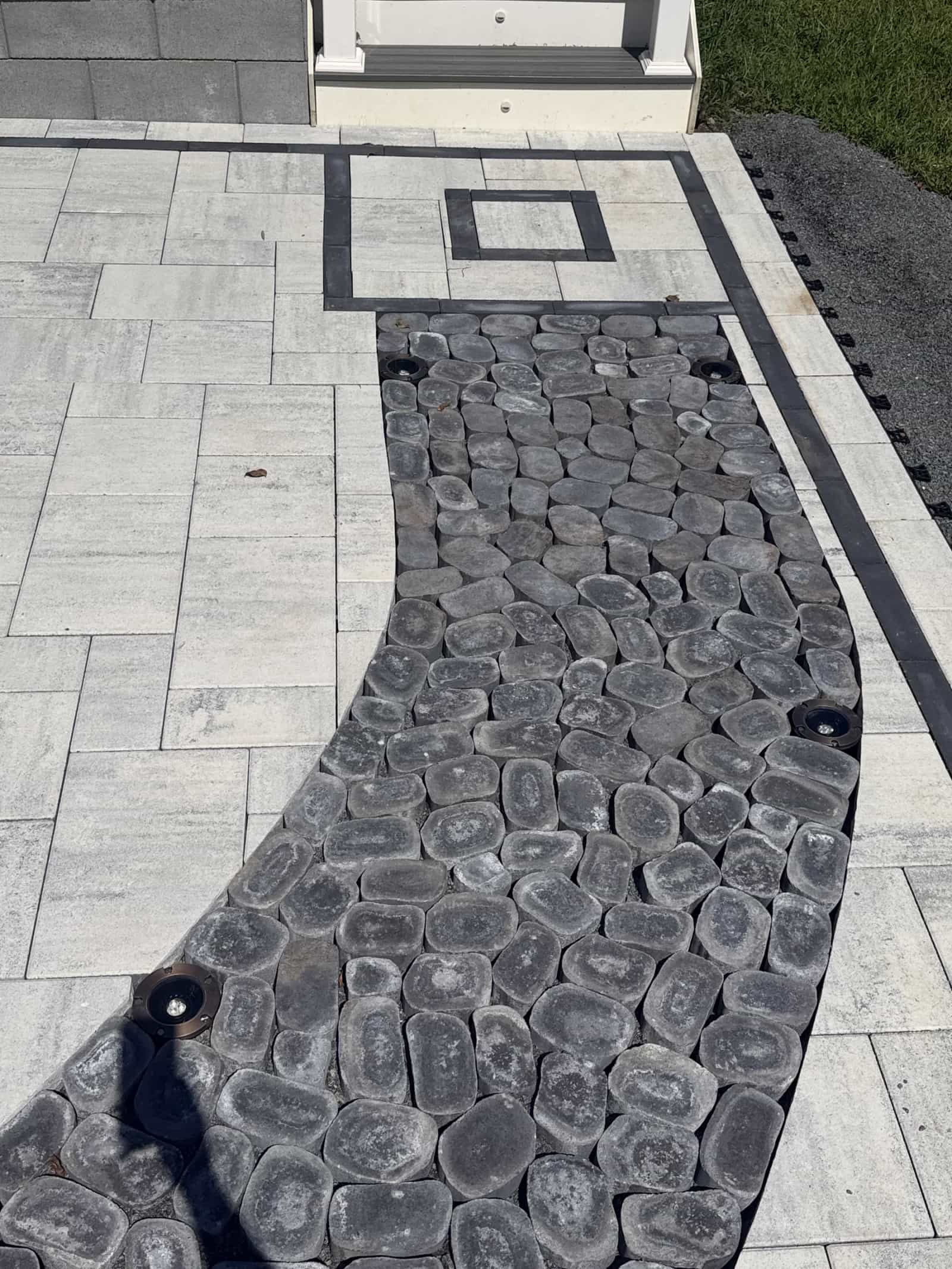 Close-up of the black cobblestone curve, fitted paver cuts and square accent near the stairs