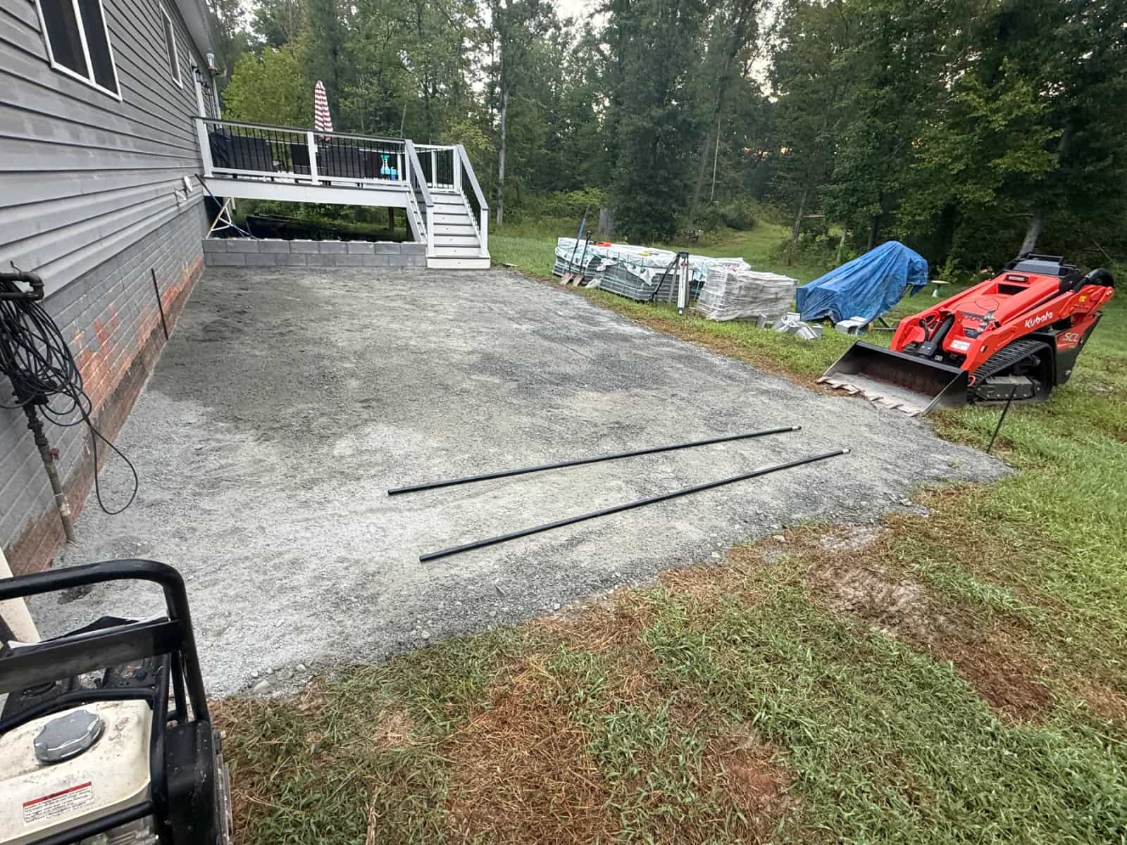 Prepared aggregate patio base beside the house before paver installation