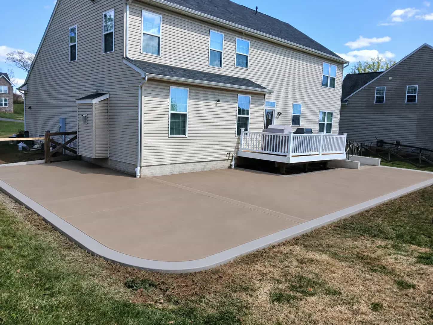 Colored concrete patio with a light gray border behind a home