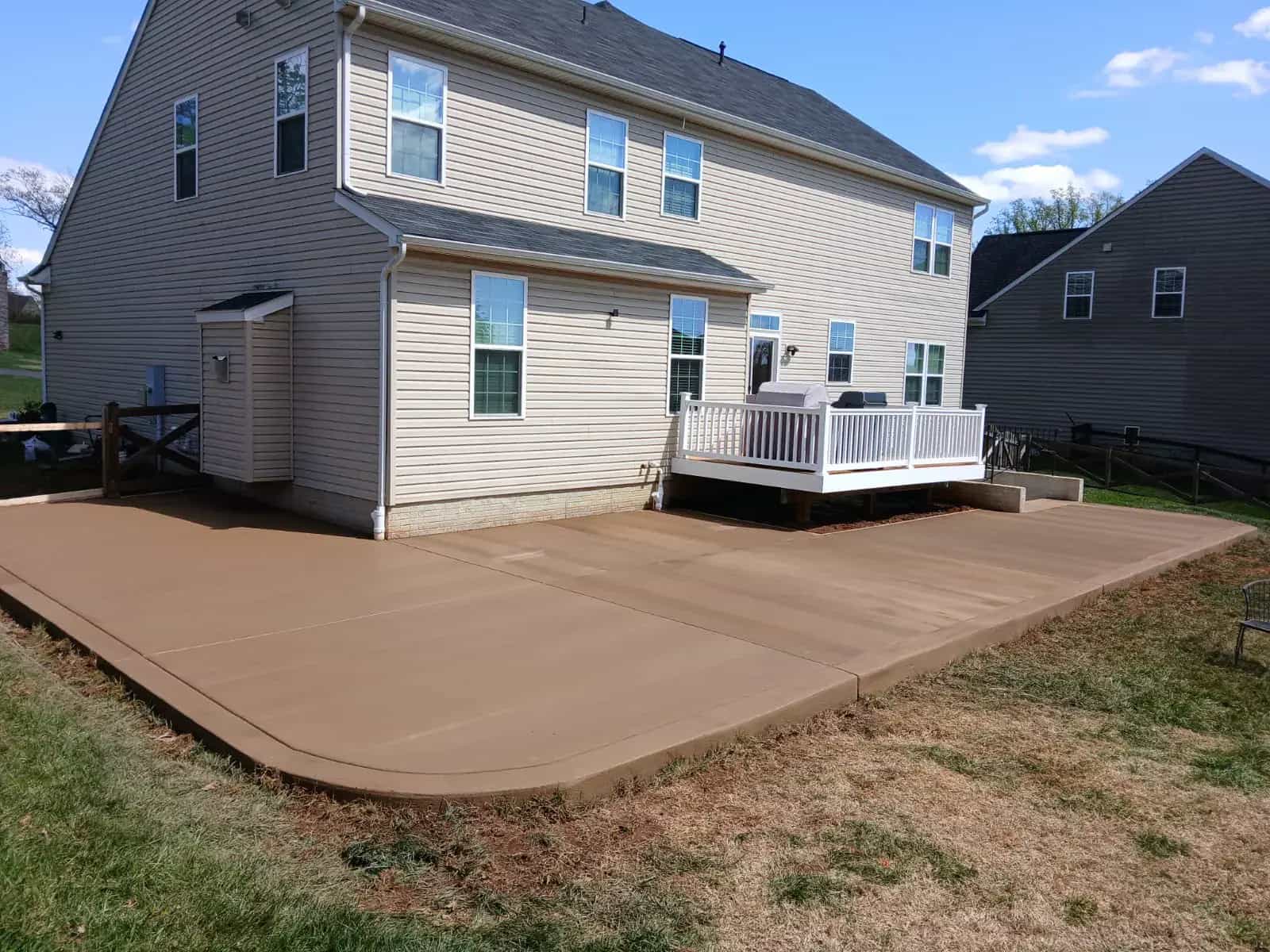 Colored concrete patio behind a home with a clean slab finish and rounded edge