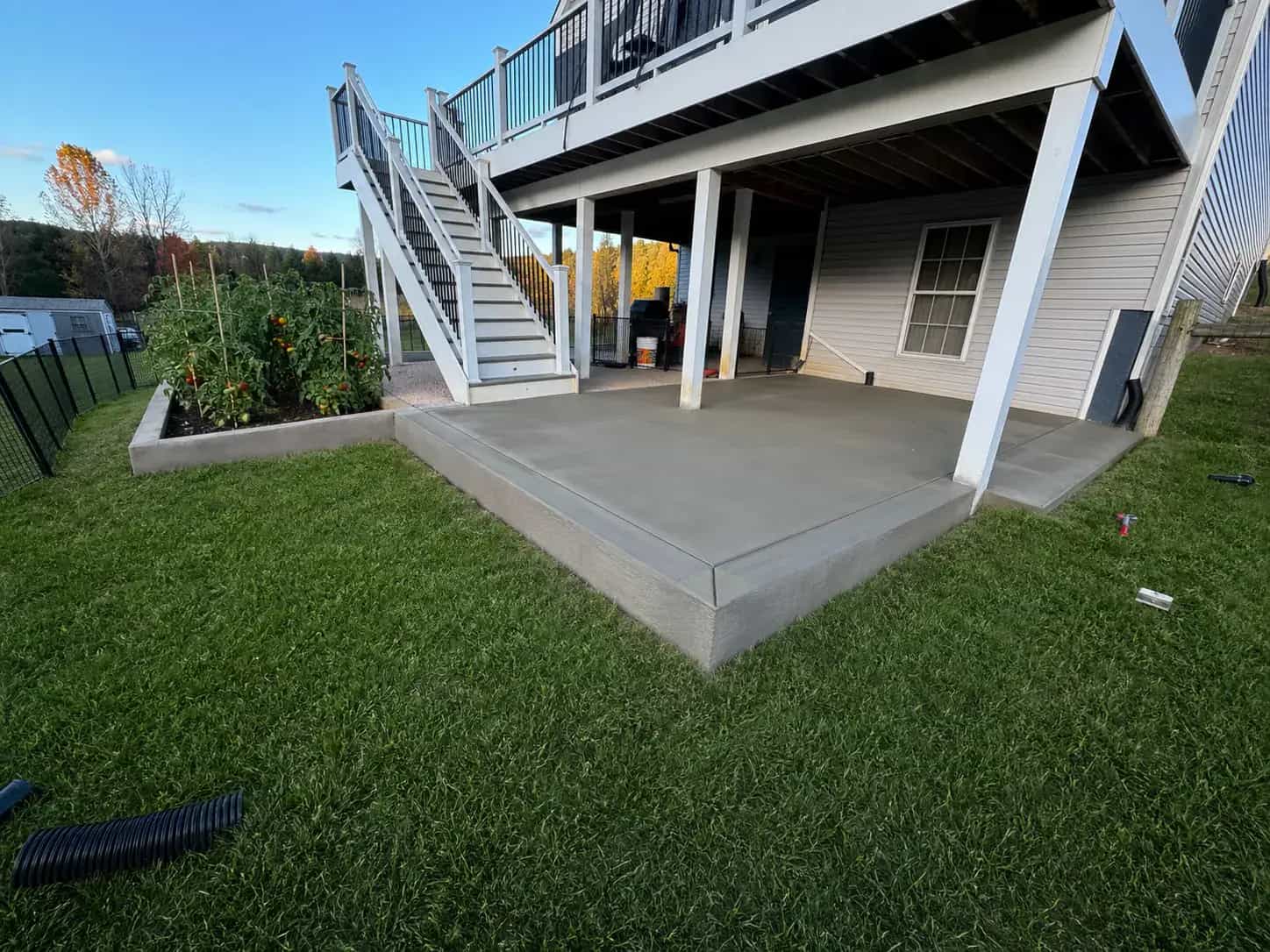 Concrete patio beside a green lawn and raised planter