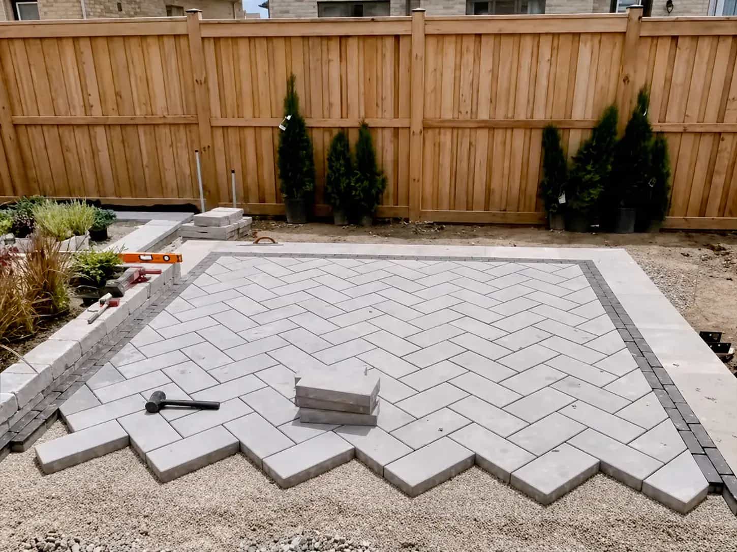 Herringbone paver patio installation with border stones and layout work in progress